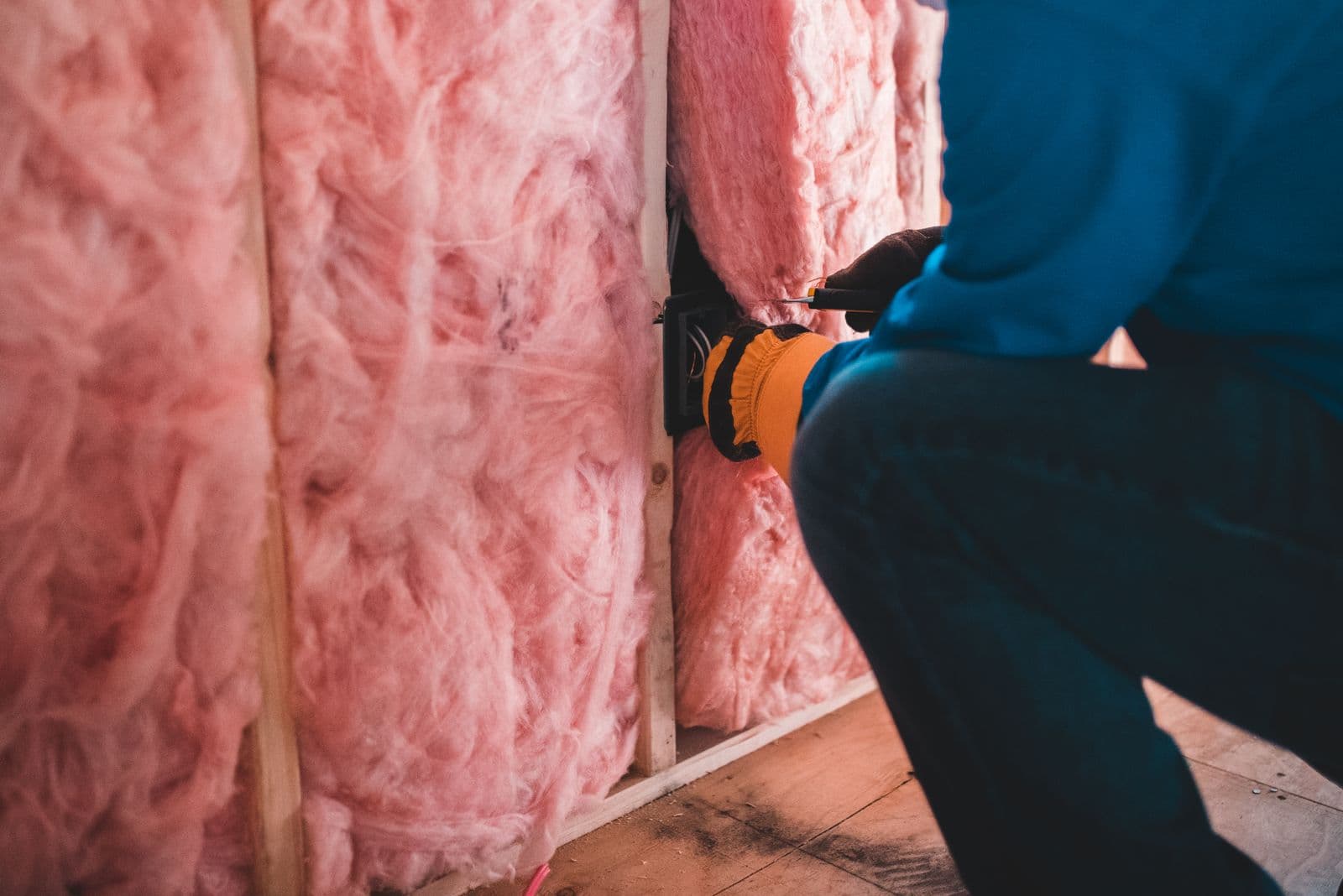 ThermoShield installer fitting fiberglass batt insulation into a wall cavity in Waco, TX